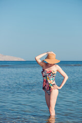 Fototapeta na wymiar pretty woman portrait in swimwear in blue sea water with an island on horizon