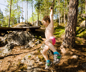 little cute boy jumping with bungee in forest, training with dad, happy family on vacations in camp, father and son