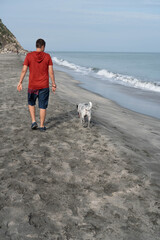 Man on his back walking a dog in the morning on the beach