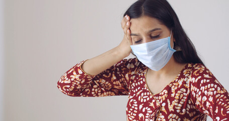 Closeup shot of an Indian girl with a headache wearing a face mask- new normal concept