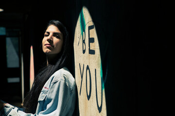Beautiful young teenager girl in casual outfit using her smartphone in the sunlight. Youth new normal lifestyle portrait concept. Copy space.