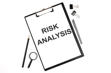 On a white background magnifier, a pen and a sheet of paper with the text RISK ANALYSIS . Business concept