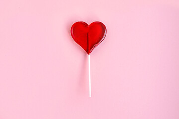 Heart shaped red lollipop on pink background