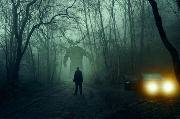 A horror concept. Of a man next to a car looking at a monster with glowing eyes. In a spooky, winter forest at night With a grunge, textured edit - obrazy, fototapety, plakaty