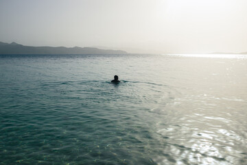 Fototapeta premium Person in Wide Ocean with Coast in Sight