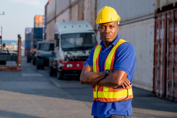 African American foreman or cargo container worker stand with confidence arm crossed in front of truck in workplace area and also look at camera.
