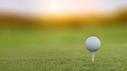 A golf ball on golf pin green grass with golf course background , green tree sun rays