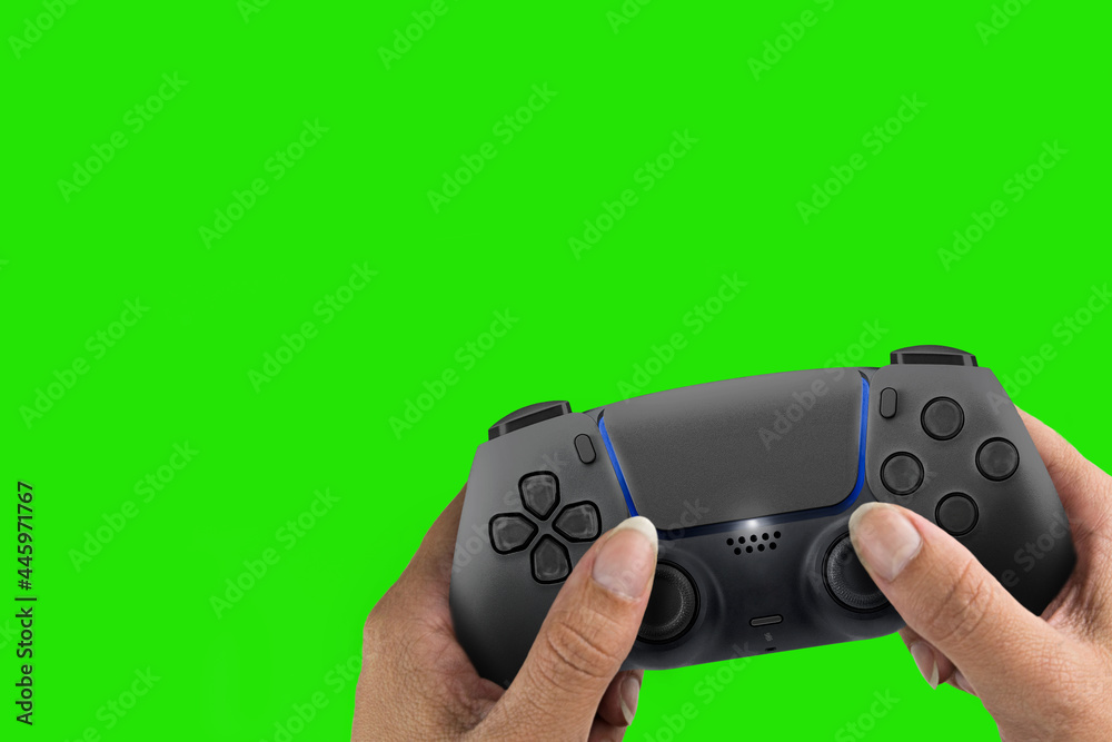 Wall mural Female hand holding a Next Generation black game controller isolated on green screen background. Chroma Key.