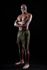 Fototapeta na wymiar Adult African American in shorts standing with arms crossed, black background