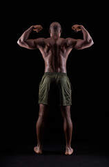 Fototapeta na wymiar Rear view of a black muscular man flexing arm muscles on a black background
