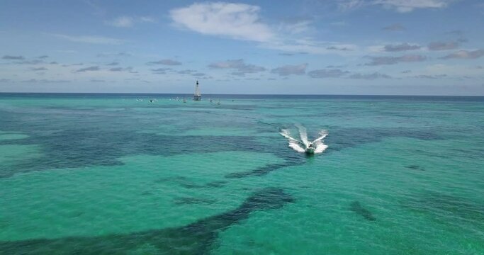 Drone footage of boat leaving Alligator Lighthouse in Atlantic Ocean off coast of Islamorada, Florida Keys in tropical blue water. Shot on Mavic Pro in 4k