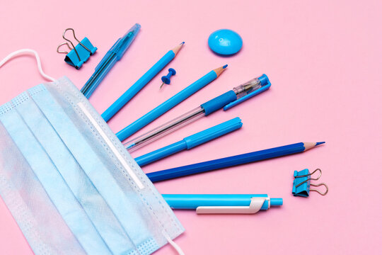 School supplies and covid 19 prevention tools. Back to school during the pandemic concept. On a pink background, blue objects