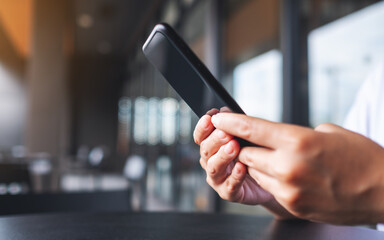 Closeup image of a hand holding and using mobile phone
