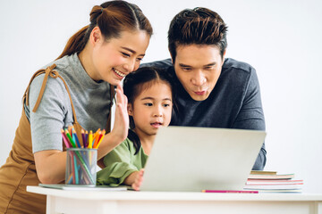 Fototapeta premium Portrait enjoy happy smiling love asian family father and mother with little asian girl learning and looking at laptop computer studying with online education e-learning system with teacher at home