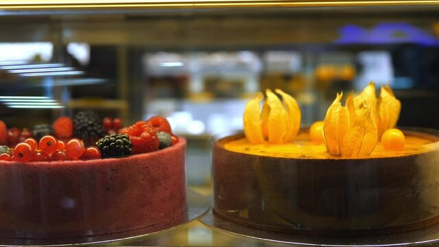 Close up of plant based cakes decorated with berries and physalis on a display in vegan confectionery shop. 