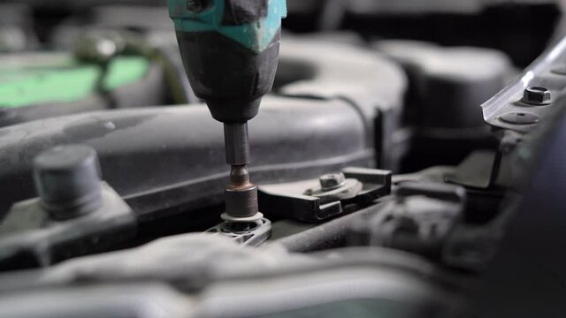 close-up of an electro screwdriver unscrews a bolt in a car, engine maintenance.