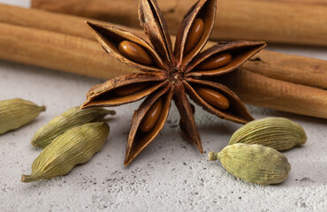 Rolls of cinnamon, cardamom and anise, closeup on a porous background, studio shot.