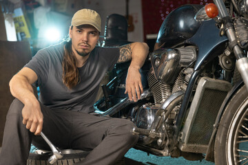 A young mechanic repairs a vintage motorcycle. Portrait, close-up.