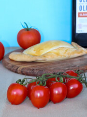 Meat pie on a cutting board and fresh red tomatoes