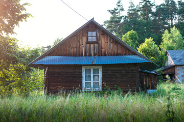 Old, wooden farm house, situated in the countryside, between the trees in the summertime. Krasnobr&oacute;d, Roztocze, Poland.