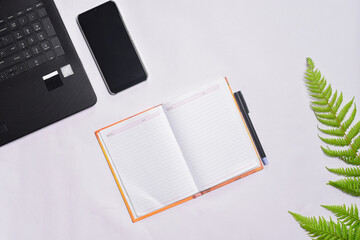 Office desk with laptop, phone, notebook and pen
