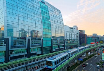 Scenery of a train traveling on elevated rails of Taipei Metro (MRT System ) under dramatic sunset sky with golden clouds reflected on the glass curtain walls of a modern office block in Neihu, Taipei