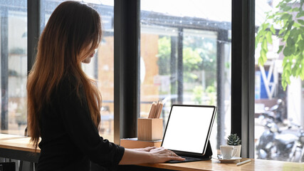 Side view of beautiful Asian woman working with laptop at cafe.