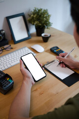 Businessman searching information on smart phone and making note on notebook.