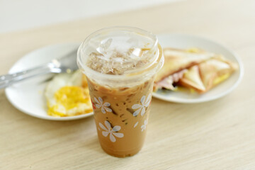 Iced coffee with breakfast on wooden table.