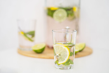 Summer cooling drink with berries and citrus. Lemonade in a reusable glass bottle and glasses. Homemade drink with mint, lime and lemon. Medicinal and healthy drink with vitamin C