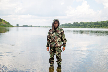 guy fisherman in a khaki suit with a mosquito net on the river