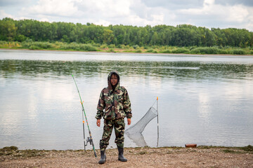 guy fisherman in a khaki suit with a mosquito net on the river