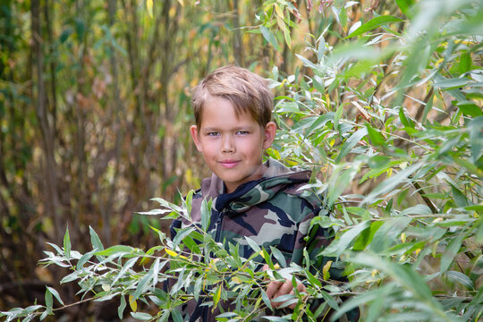 portrait of a boy in a protective suit peeking out of the bushes