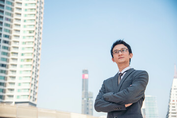 Asian businessman wear suit, eye glasses standing street in modern city. Portrait Young handsome asian man look at bright future smart, confident. Entrepreneur executive man cityscape outside office