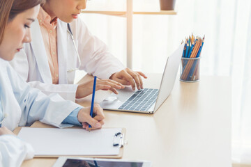 Asian medical lab young women talking together discussing healthcare assistance teamwork. Two asian women doctors discuss meeting doctor's office medical clinic using laptop consulting patient disease