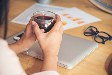 Close up hands of woman sitting office desk holding sweet coffee cup relax and enjoy with happy time. Hot coffee mug in hand. Woman holding coffee cup relaxing after work at office warm taste in cafe