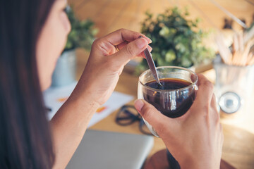 Fototapeta na wymiar Woman holding coffee cup relaxing after work at office warm taste in cafe. Close up hands of woman sitting office desk holding sweet coffee cup relax and enjoy with happy time. Hot coffee mug in hand