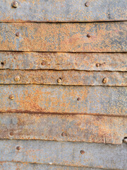 an old rusty wall or garage door made up of several metal plates connected by rivets and nails