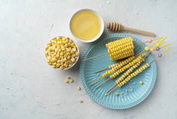 Delicious juicy sweet boiled corn in a plate on a white concrete background, cooked corn cobs