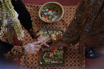 Hands of an Asian woman wearing beautiful henna. a woman washes a man's feet, wedding procession photo concept.