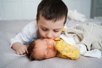 older brother kisses newborn sister. birth of second child in family.
