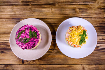 Traditional russian new year layered salads Mimosa and Herring under a fur coat (shuba) on wooden table. Top view