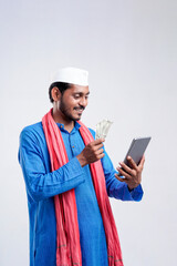 Young indian farmer using smartphone and showing money on white background.