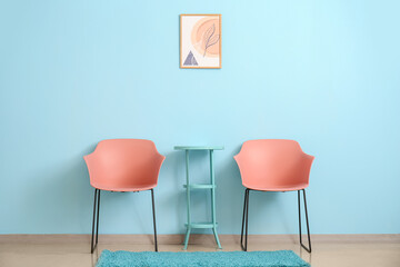 Modern armchairs and table near color wall