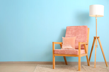 Stylish armchair and lamp near color wall