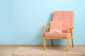 Fototapeta na wymiar Stylish armchair with pillow near color wall