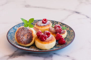 Cottage cheese pancakes or syrniki with raspberry and sugar powder. Healthy breakfast.