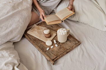coffee in bed. shapely female legs in warm socks, wooden tray for breakfast in bed. two cups of coffee and marshmallows. the concept of cozy home. top view