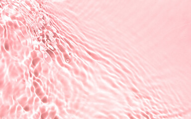 Blurred or defocused transparent clear water waves in sunlight.  Pink liquid colored clear water...