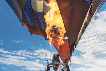 Hot flame from a gas burner light up inside of a hot air balloon at evening.